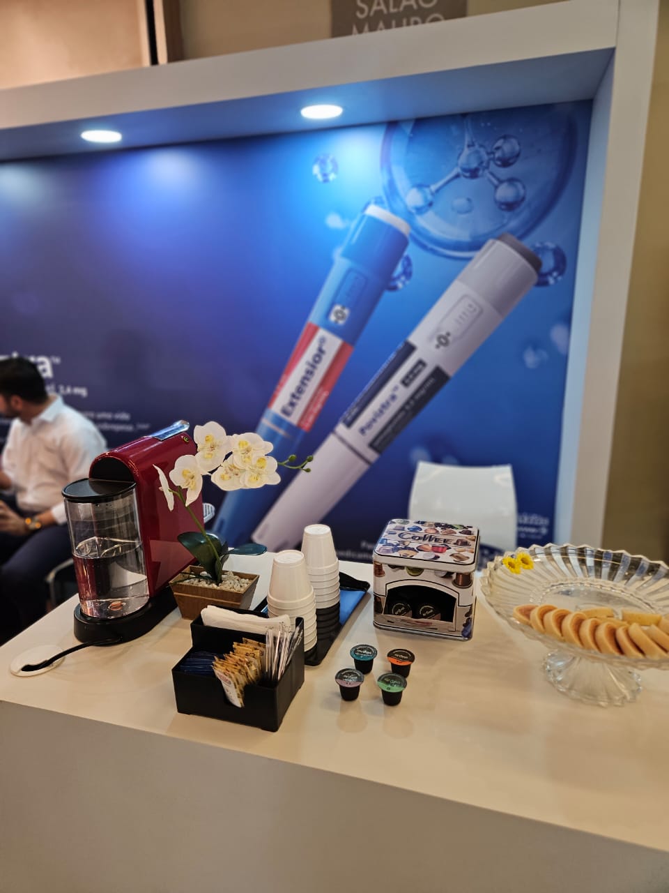 Detalhes de uma estação com cafeteira, cápsulas, copos e biscoitos
